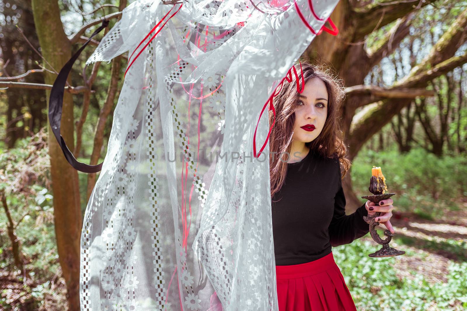 mysterious woman witch in the woods with a candle hidden behind the curtains