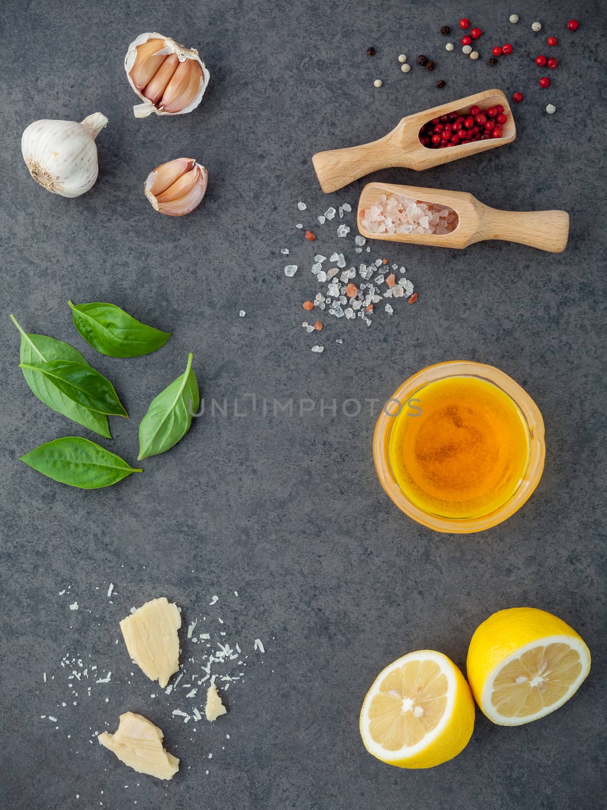 The ingredients for homemade pesto sauce basil, parmesan cheese ,garlic, olive oil , lemon ,pine nut ,pepper corn and himalayan salt on dark stone background with flat lay and copy space.