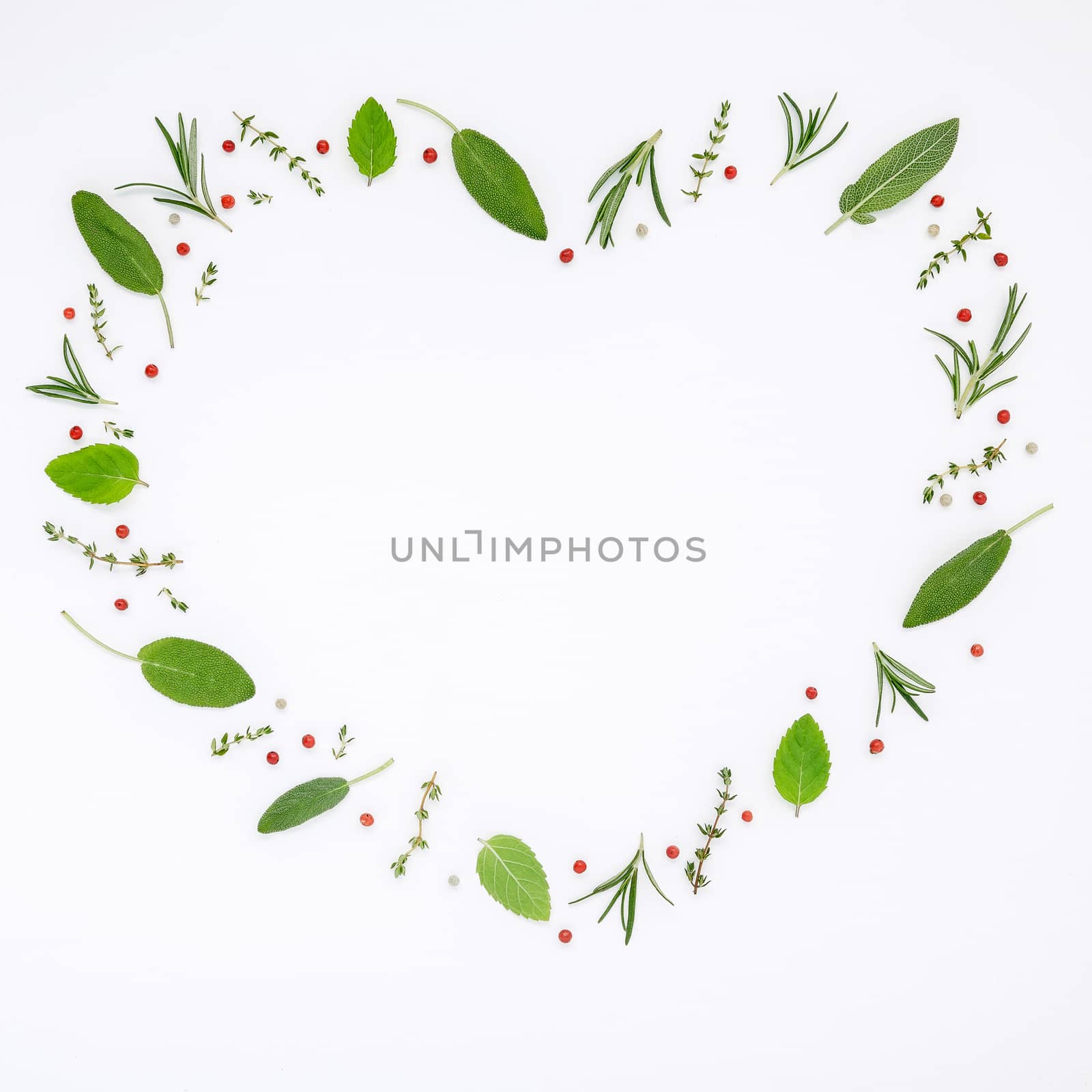 Heart shaped frame various fresh herbs rosemary, sage ,thyme and peppermint leaves flat lay with central copy space on white wooden background.