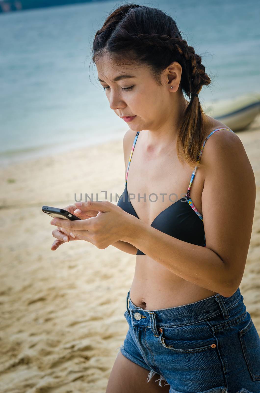 Beautiful young woman uses a smartphone on the beach. Filter vintage