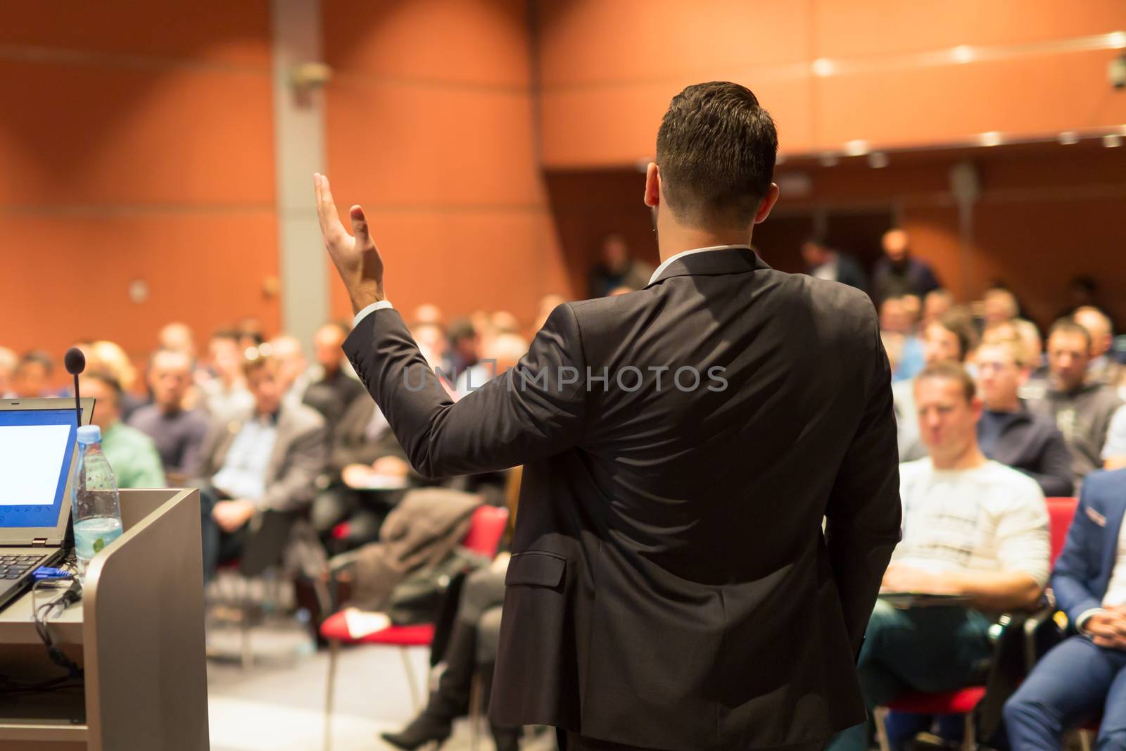 Speaker giving a talk on corporate business conference. Audience at the conference hall. Business and entrepreneurship event.