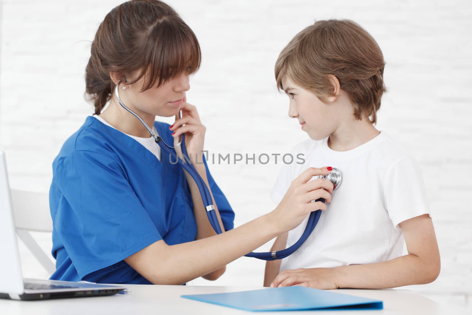 Female doctor listening to heartbeat of a boy, isolated on white