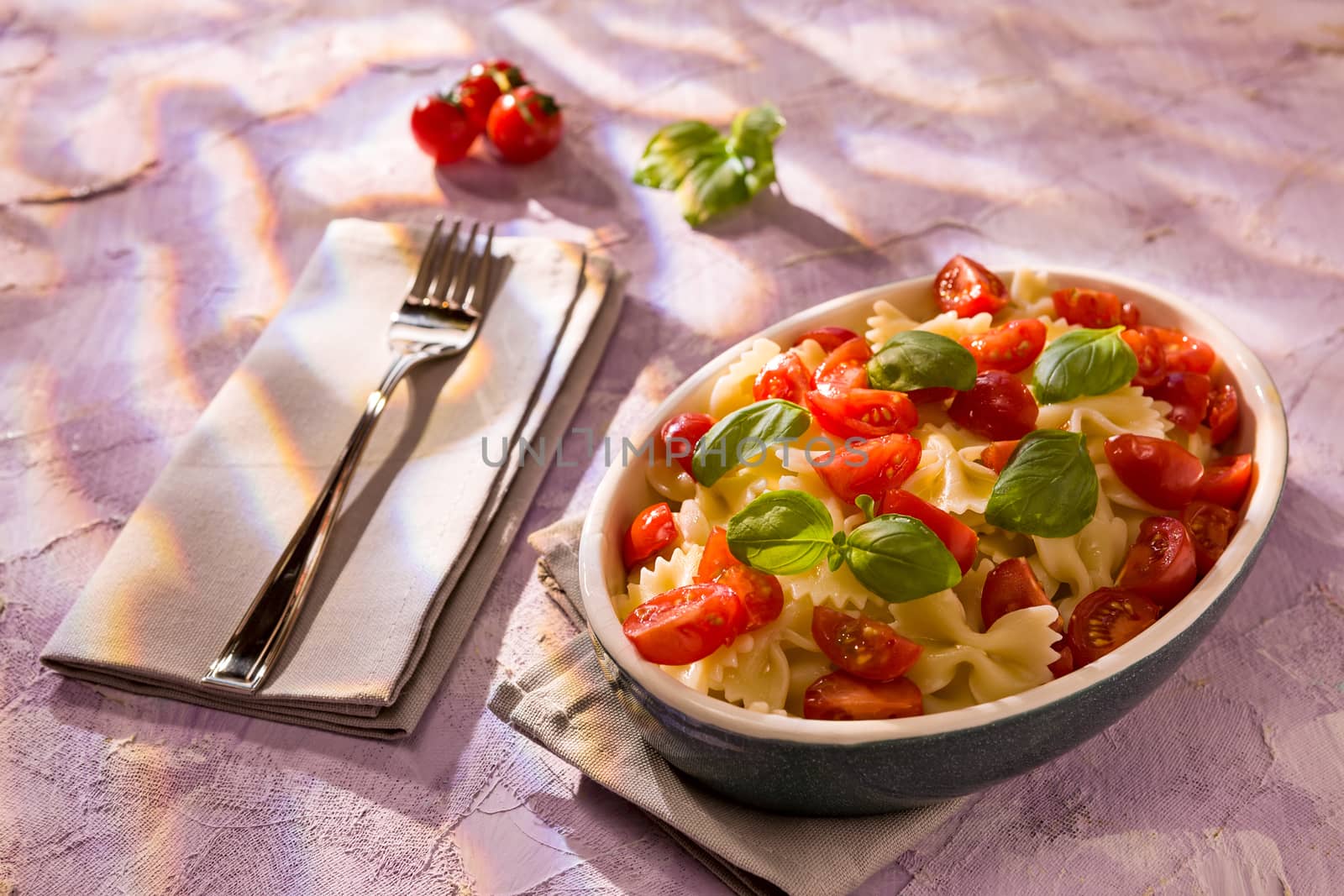 Italian Farfalle pasta with tomatoes and basil over a colored ba by LuigiMorbidelli