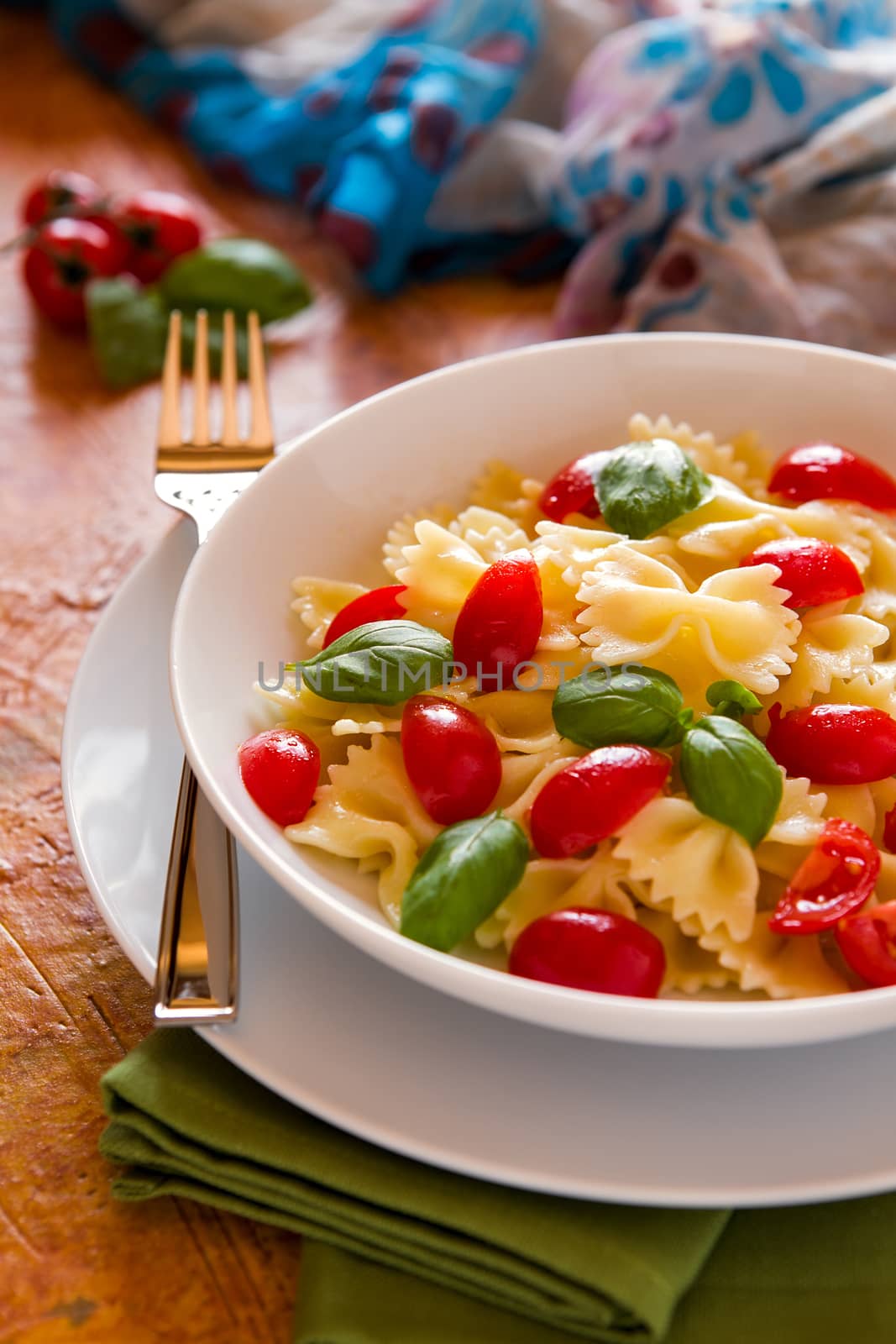 Farfalle pasta with cherry tomatoes and basil over a green napkin