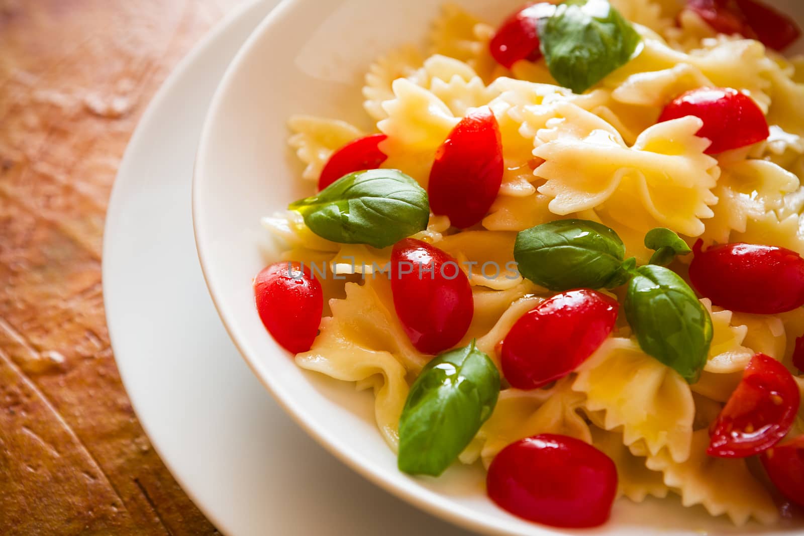 Closeup of Farfalle pasta with cherry tomatoes and basil over a  by LuigiMorbidelli