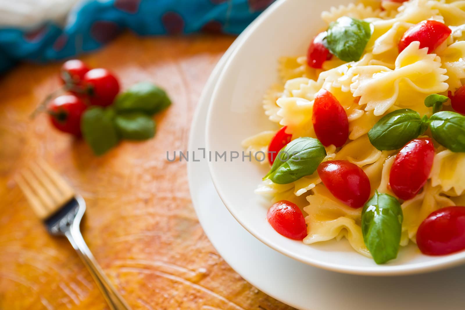 Closeup of Farfalle pasta with cherry tomatoes and basil over a  by LuigiMorbidelli