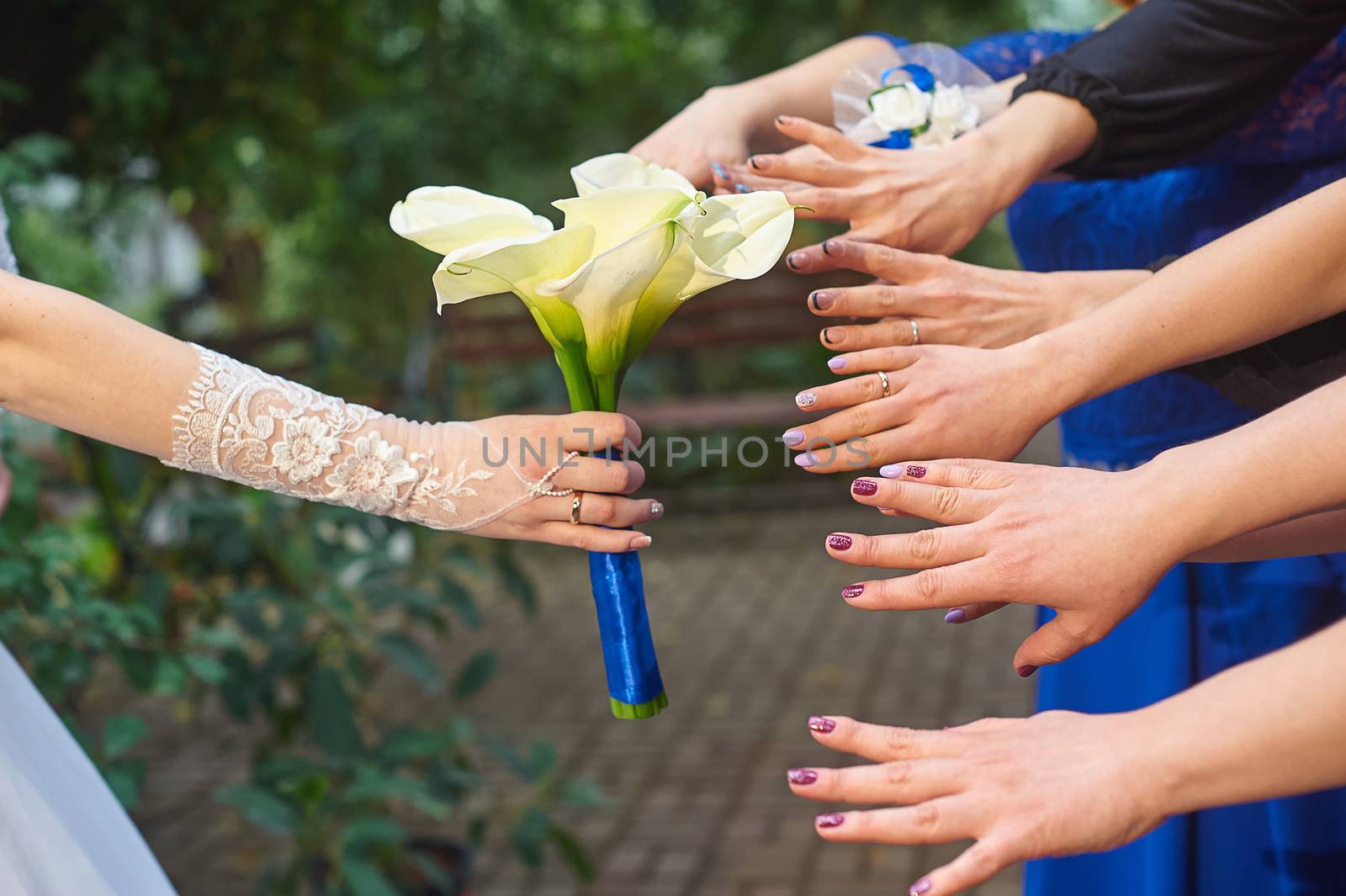 hands of bridesmaids are drawn to a wedding bouquet of callas.
