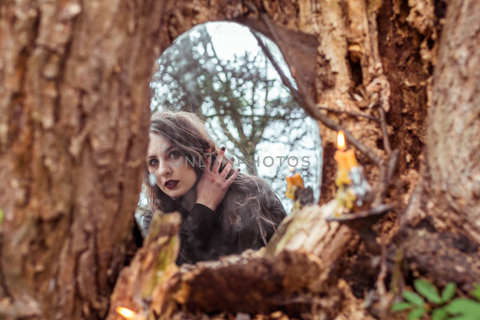 mystical woman looks in the mirror near a tree at the spring forest