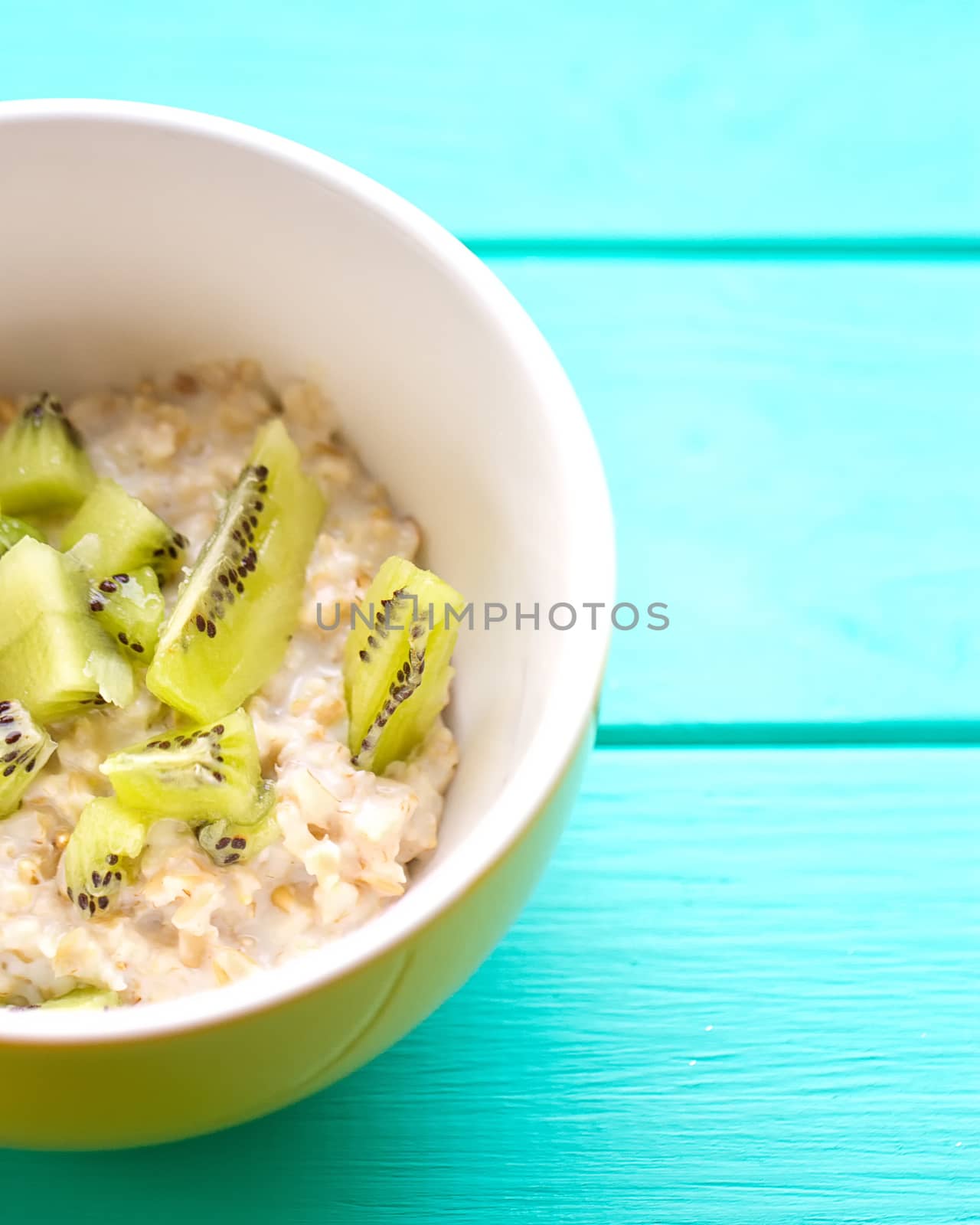 Oatmeal with milk and kiwi in a yellow bowl by victosha