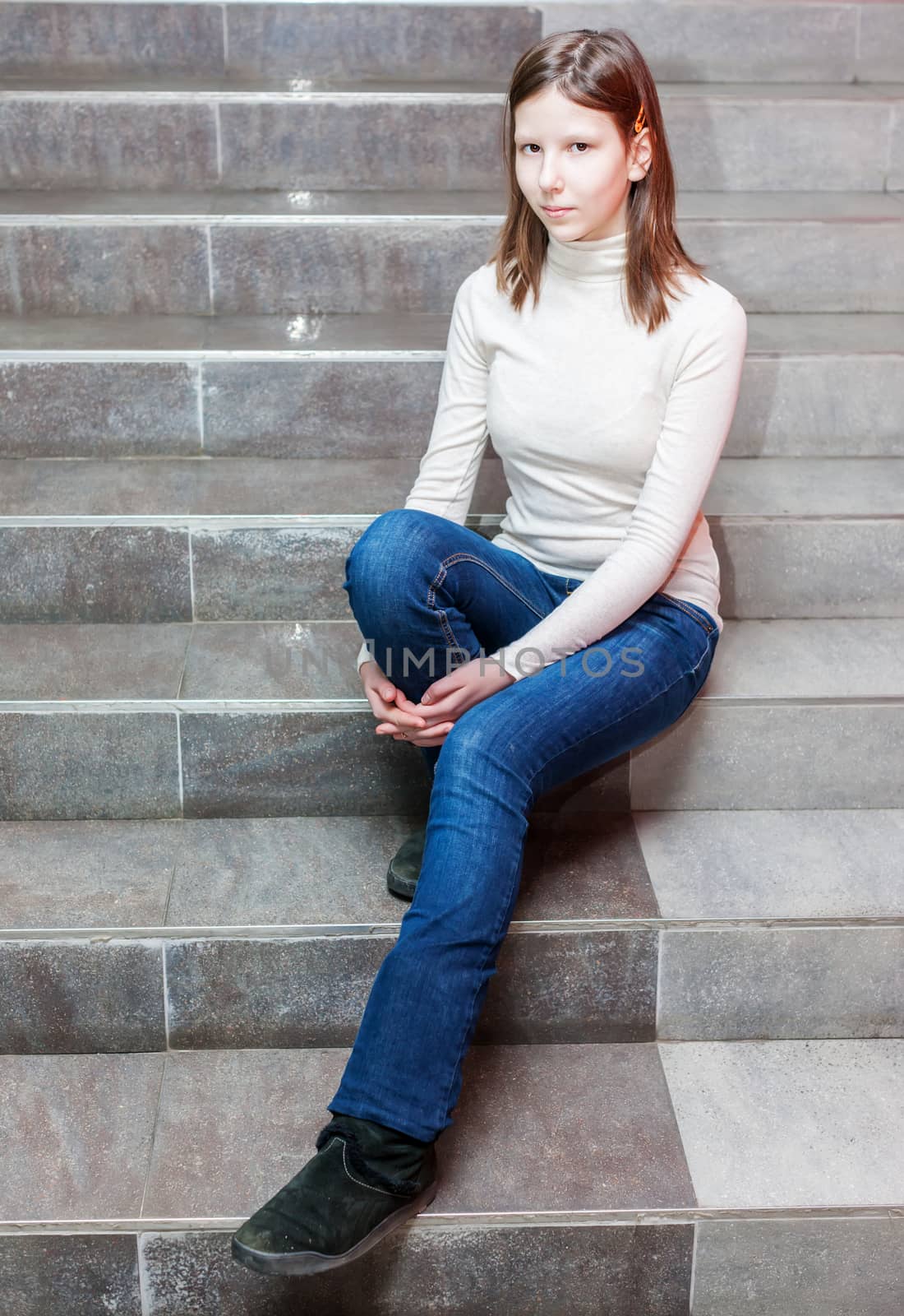 teen girl sitting on stairs. Indoor portrait of a sad teenage girl 