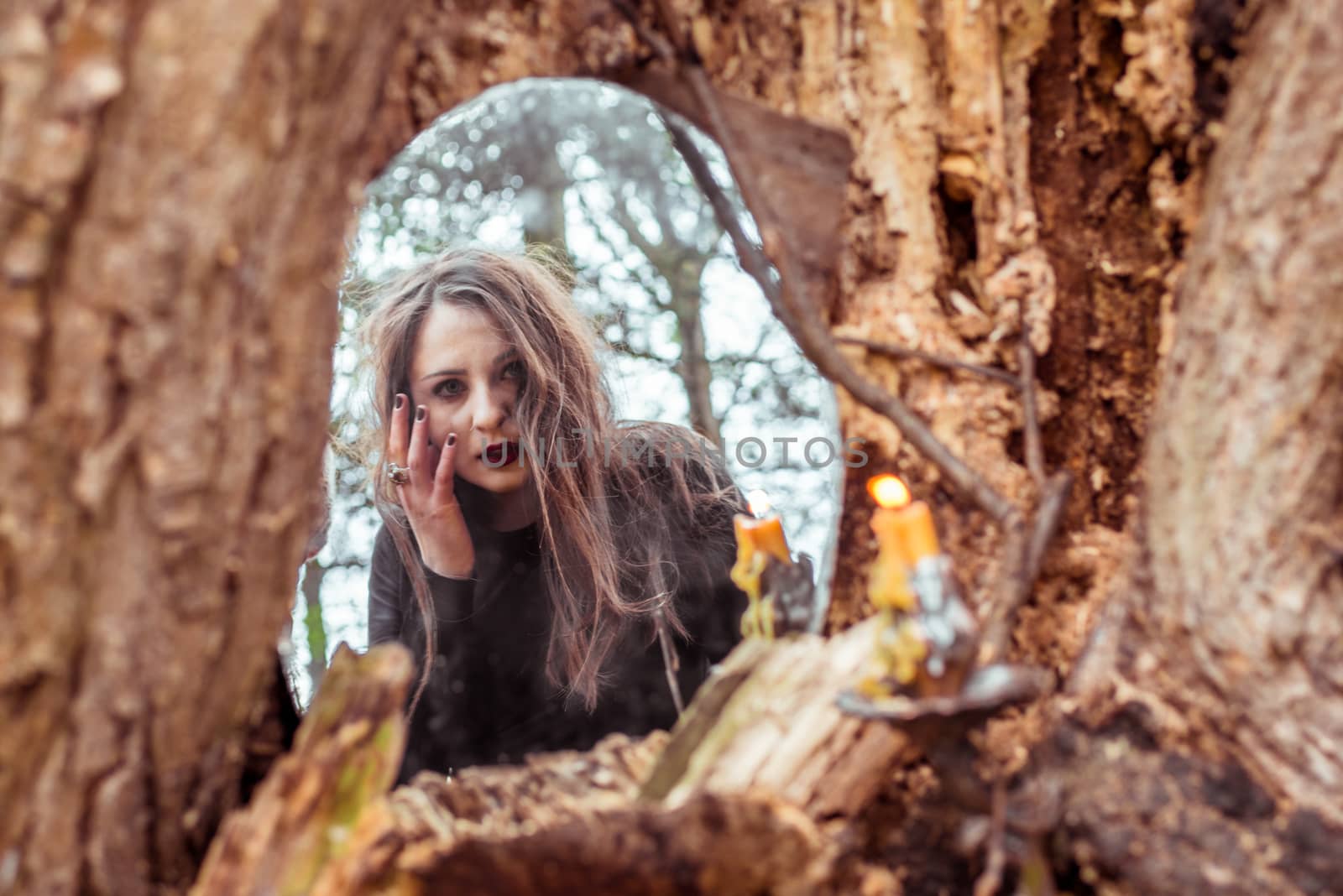 mystical woman looks in the mirror near a tree at the spring forest