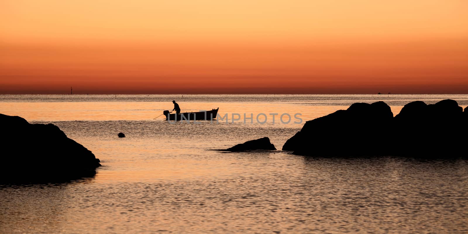 Fisherman in the early morning dawn waiting to get back into the boat to its network
