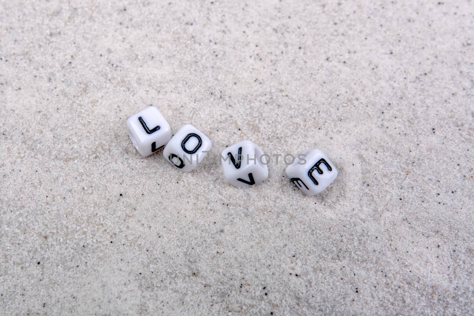 White boxes with love inscription on a grey sand