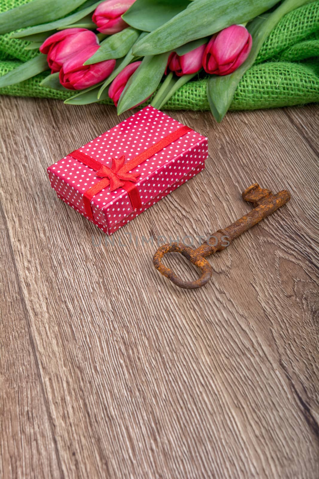 Red tulips, rusty key and red gift on a wooden background