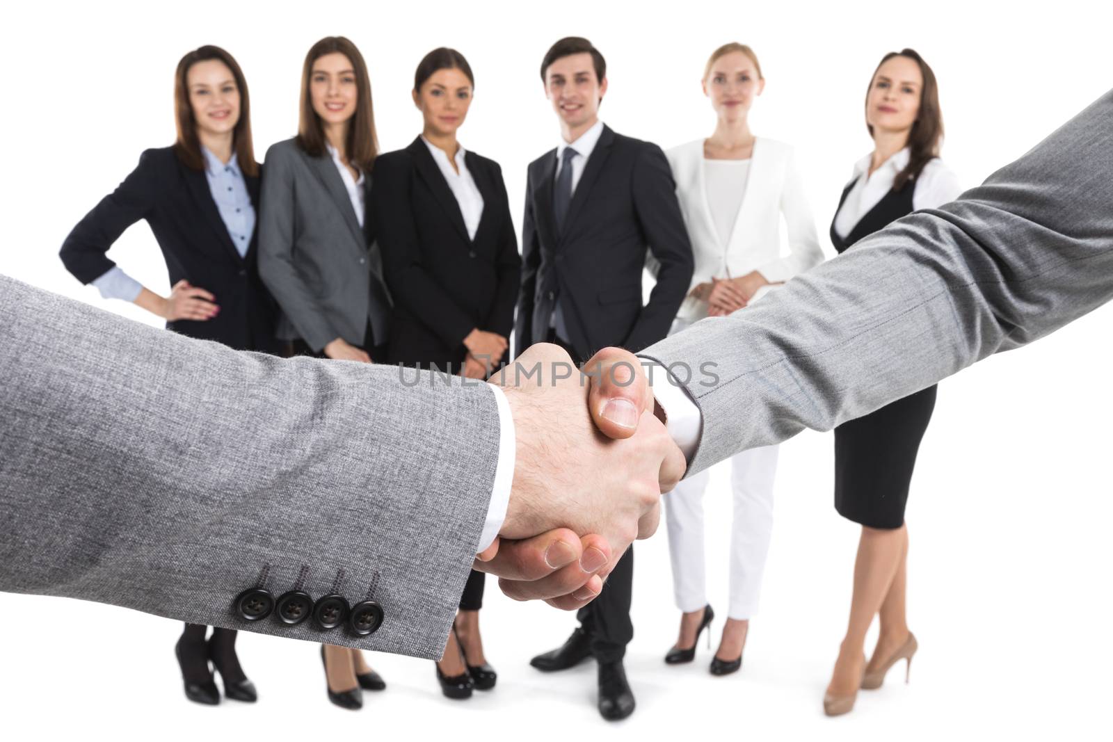 Closeup of business handshake, team of business people on background, isolated on white