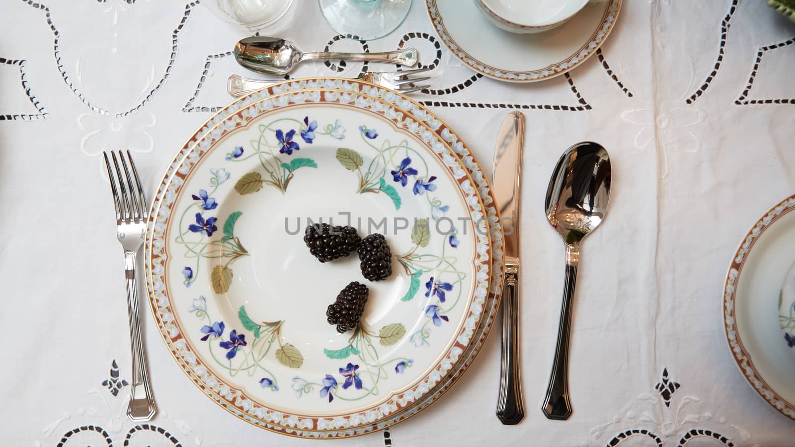 Decorated table ready for dinner. Beautifully decorated table set with flowers, candles, plates and serviettes for wedding or another event in the restaurant.