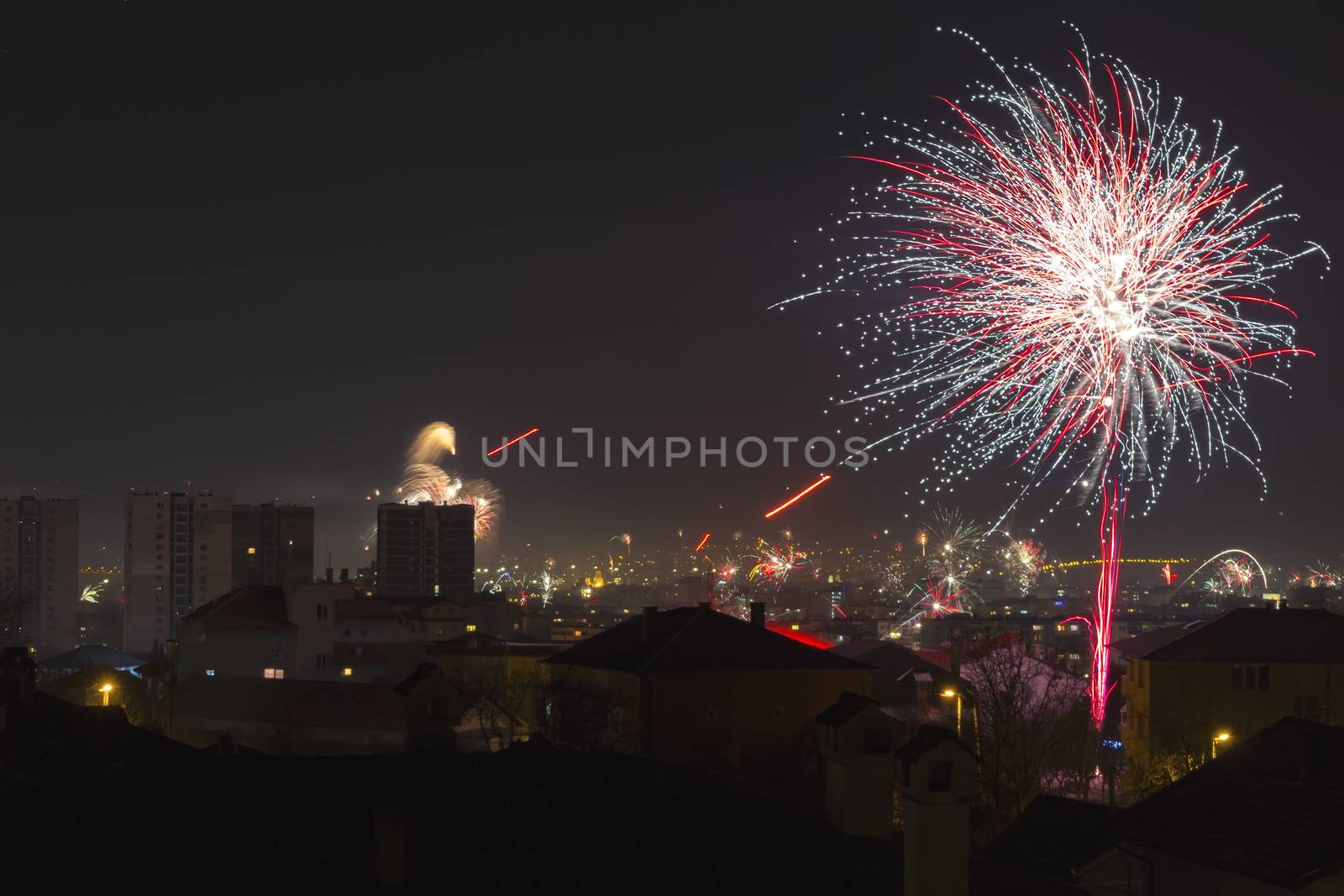 Colorful fireworks celebration and the city night light background.