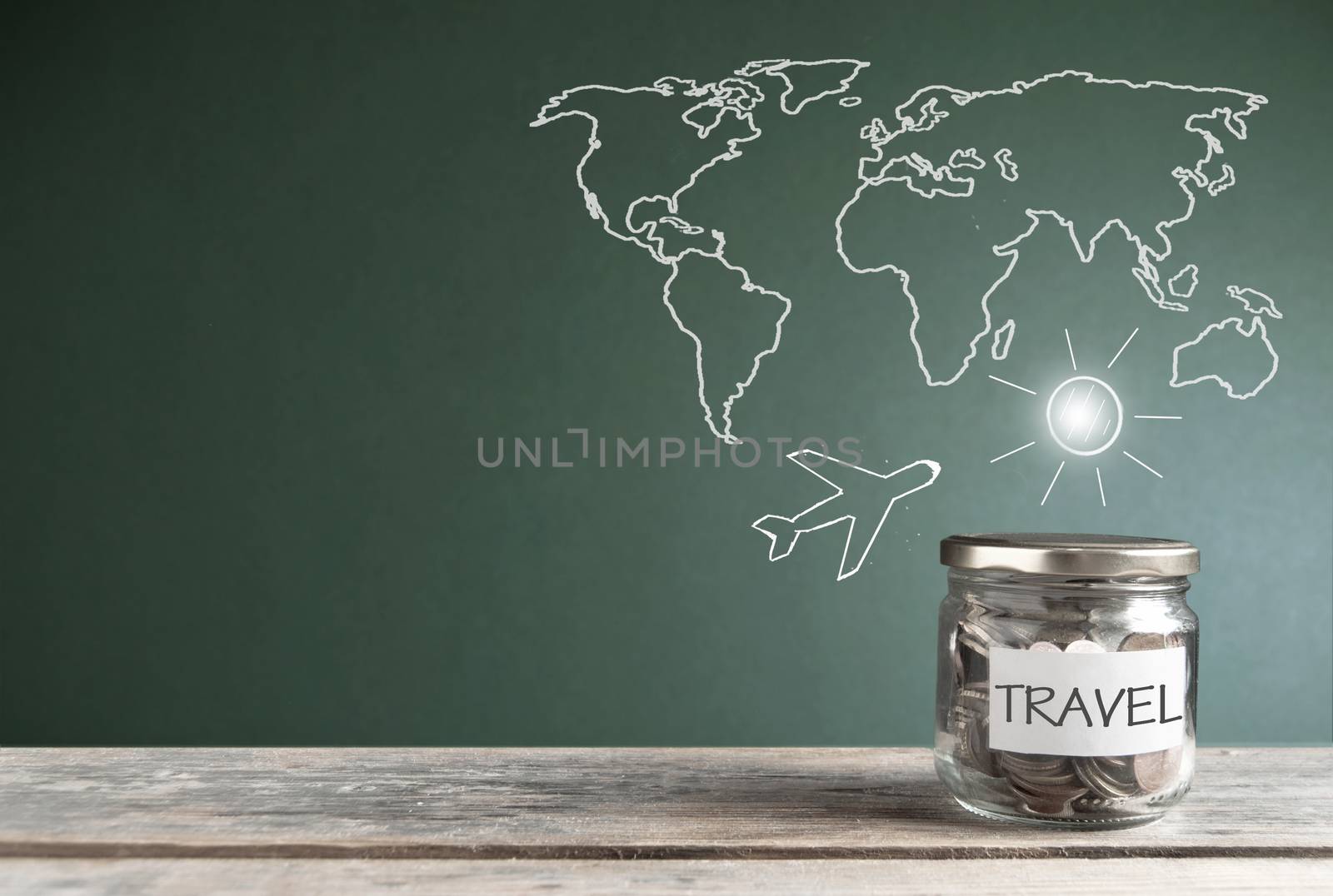 Travel savings jar by a chalkboard with a world map