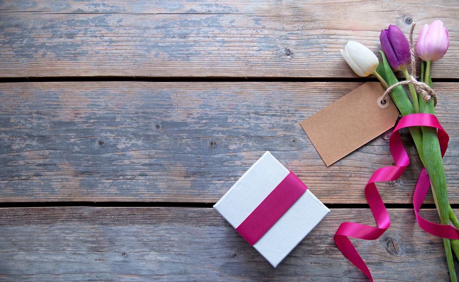 Flowers with blank gift label over a wooden background