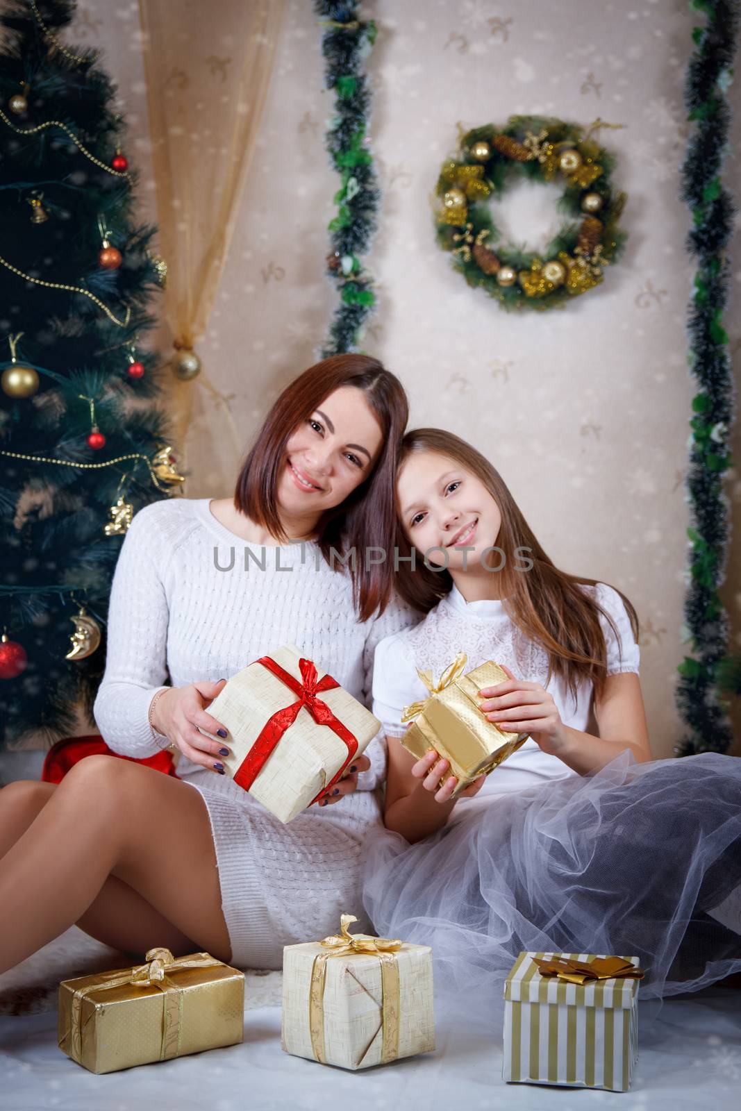 Smiling daughter and mother holding Christmas gifts