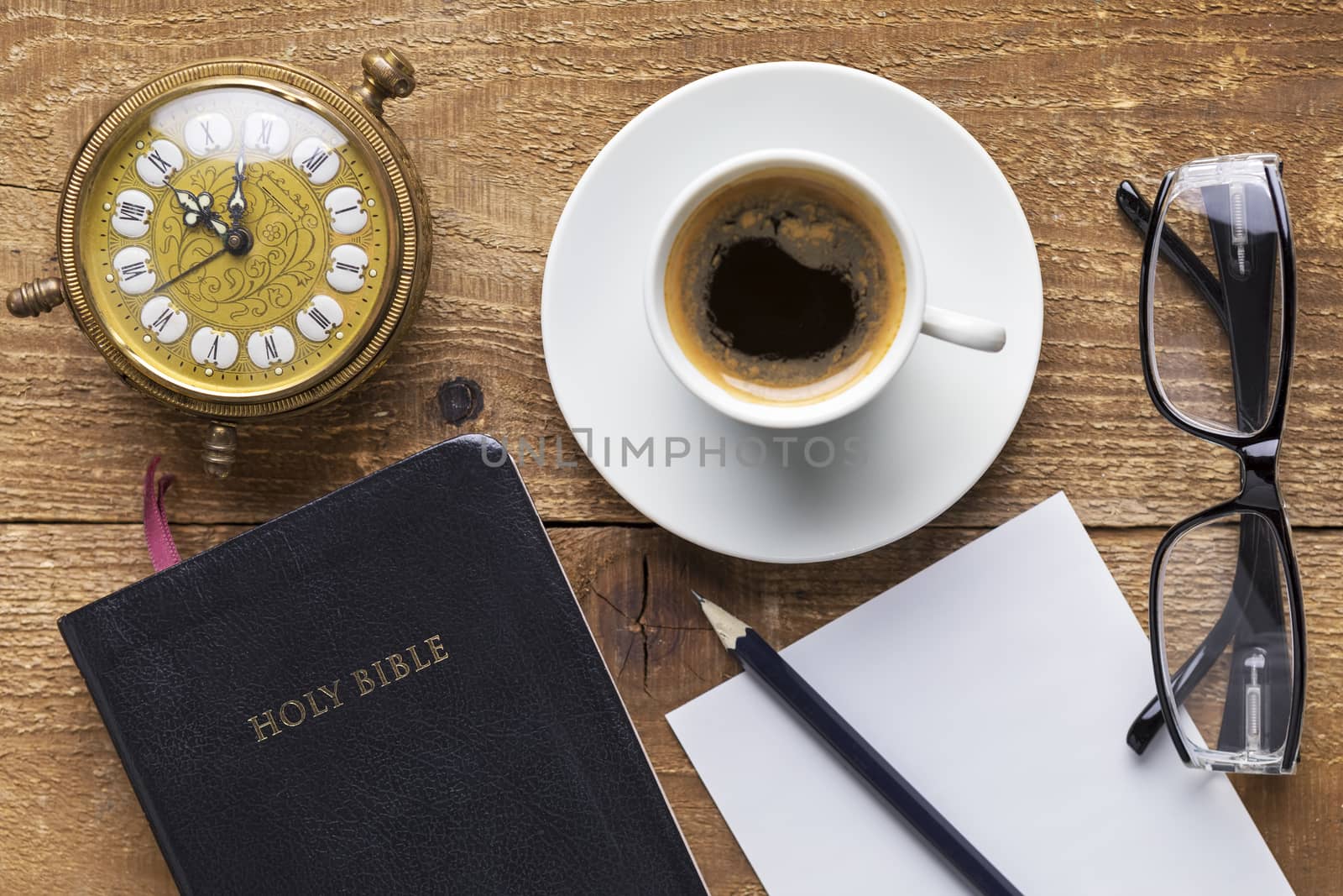 Holy Bible, alarm clock, glasses and coffee on wood table. Studying  the Bible concept. Focus on the Bible