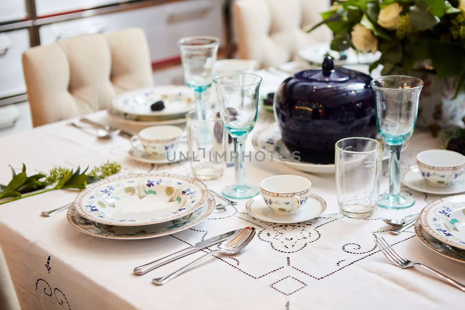 Decorated table ready for dinner. Beautifully decorated table set with flowers, candles, plates and serviettes for wedding or another event in the restaurant.