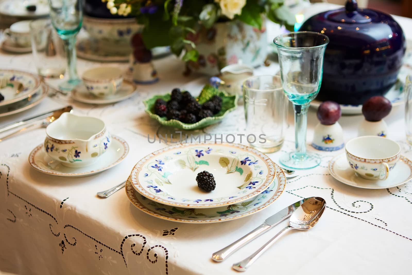 Decorated table ready for dinner. Beautifully decorated table set with flowers, candles, plates and serviettes for wedding or another event in the restaurant.