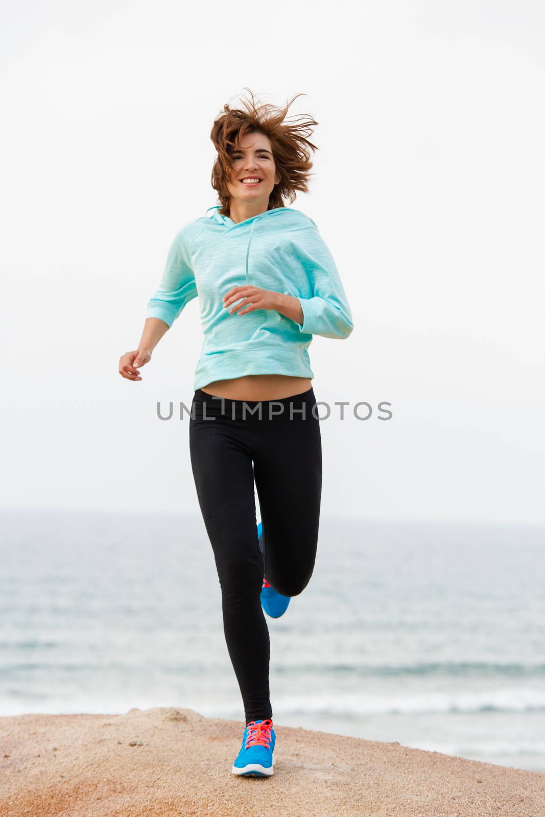Beautiful happy woman running on the beach 