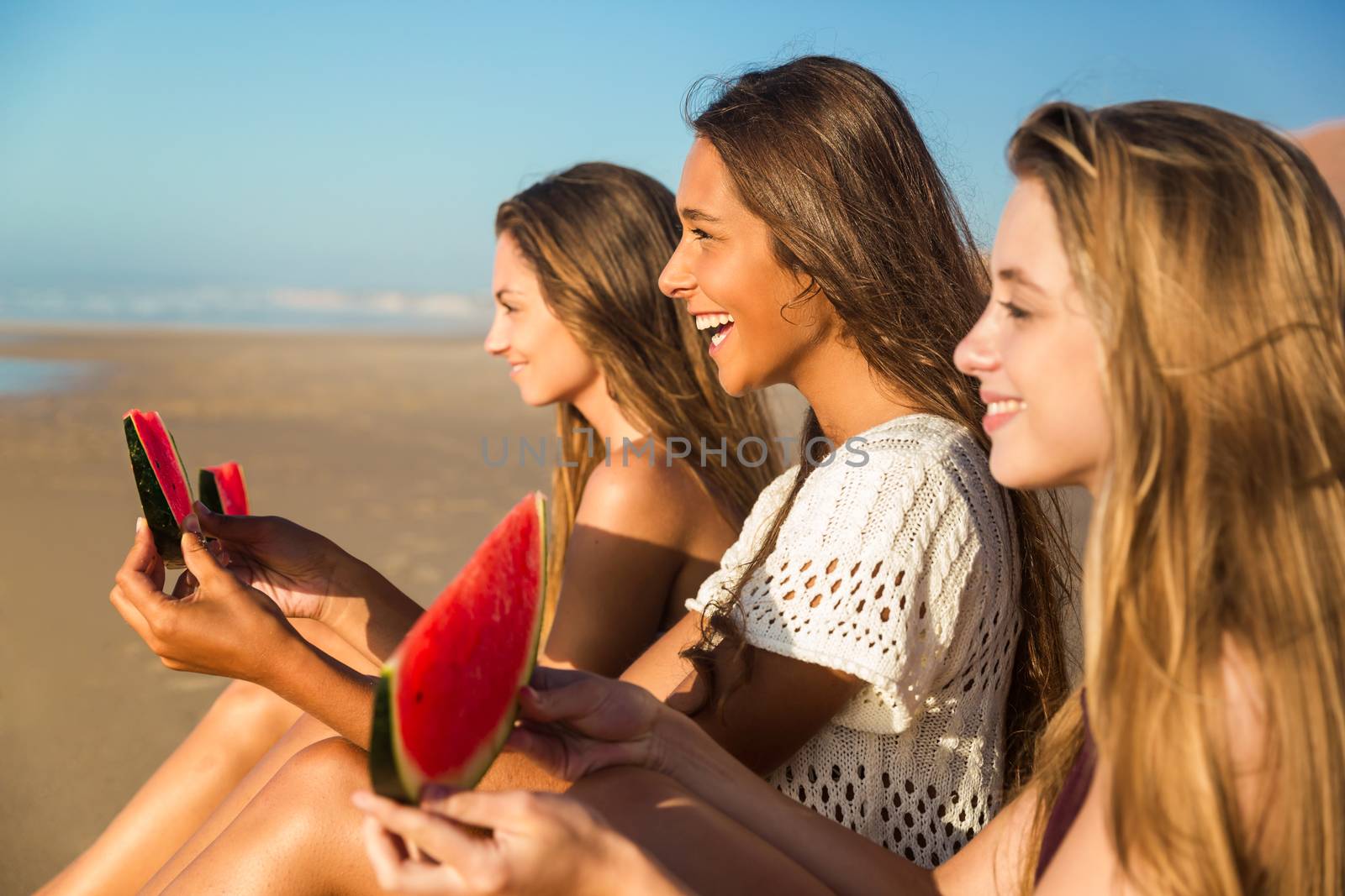 Best friends having fun on the beach and eating watermelon