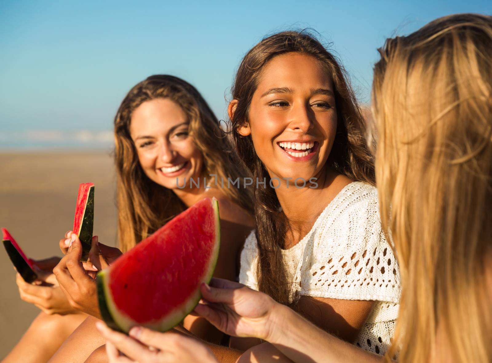 Best friends having fun on the beach and eating watermelon