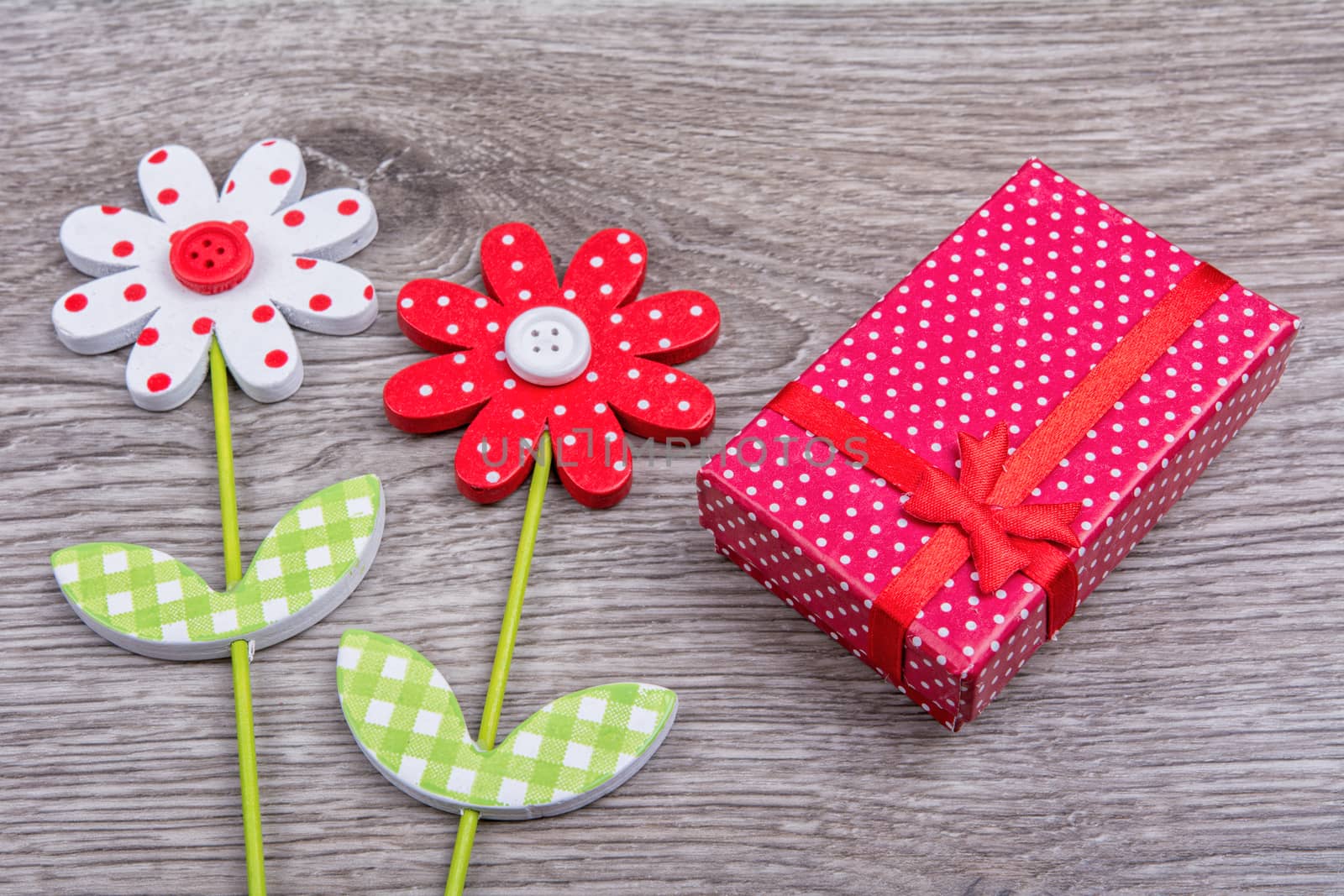 Wooden flowers with red gift on wooden background