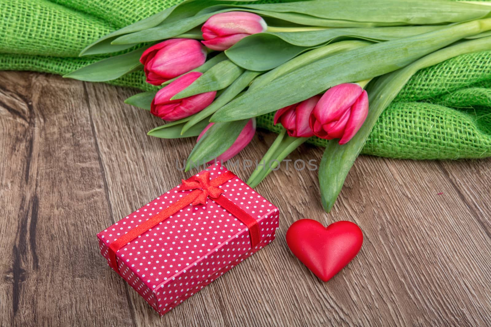 Red tulips, heart and red gift on a wooden background