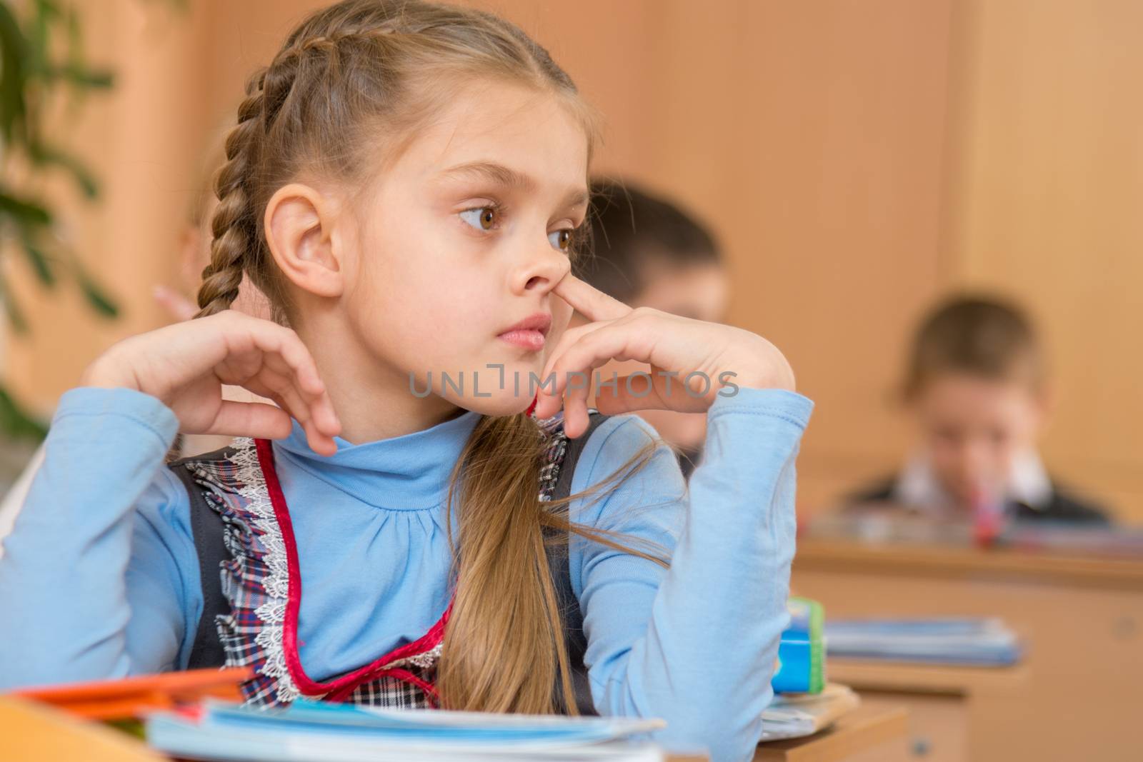 The girl at a lesson at school picking his nose