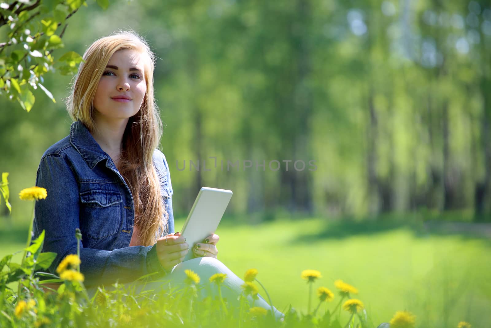 Young woman using tablet in spring park with flowers