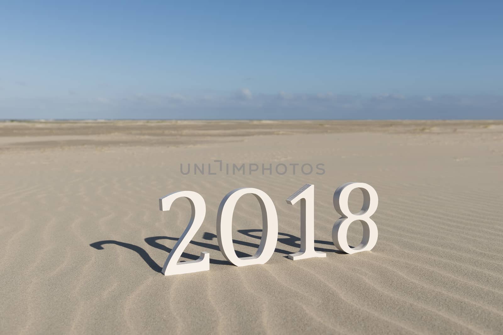 White wood figures on a beach forming the text two thousand eighteen as conceptual welcoming of the coming new year
