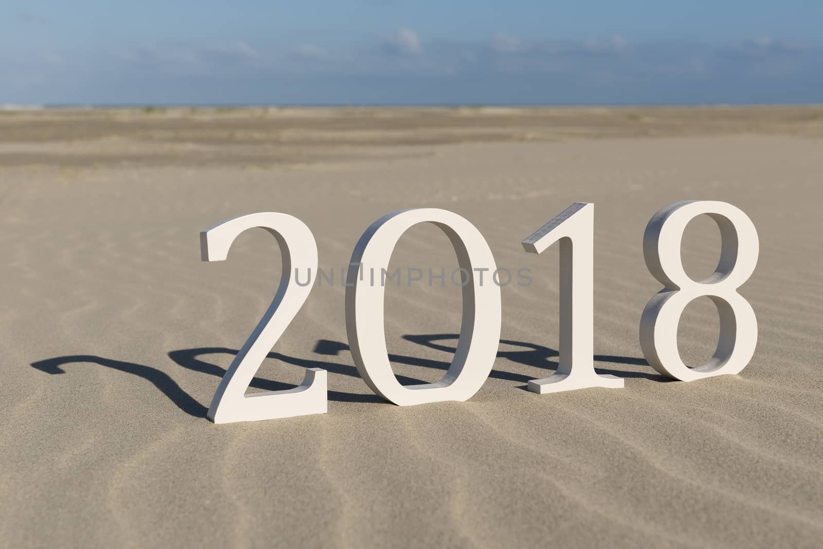 White wood figures on a beach forming the text two thousand eighteen as conceptual welcoming of the coming new year
