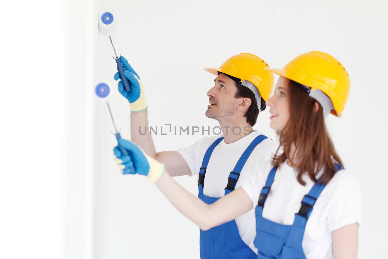 Team of young workers in hardhats painting the wall