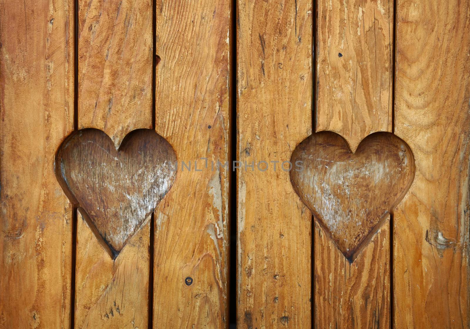 Two heart shapes carved in vintage wood close up by BreakingTheWalls