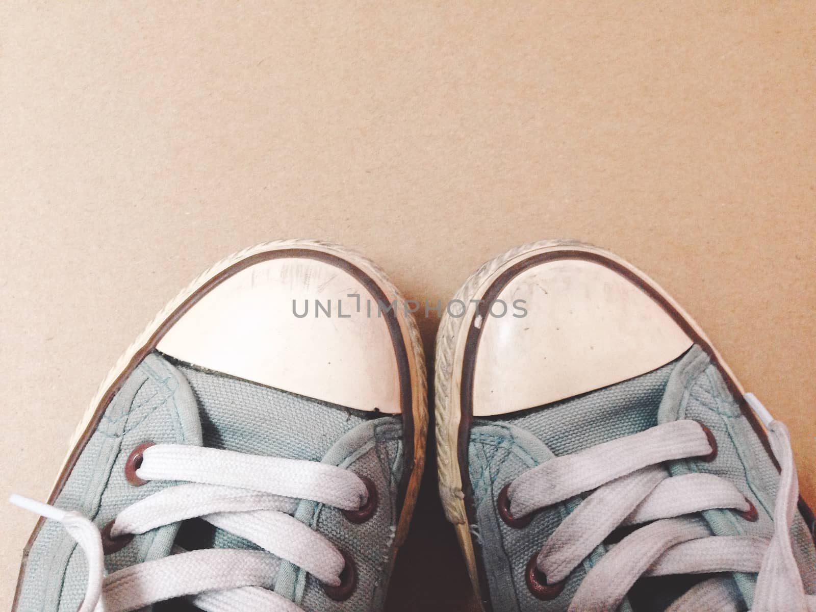 Dirty shoes top view of blue sneakers display on brown background. Vintage effect.