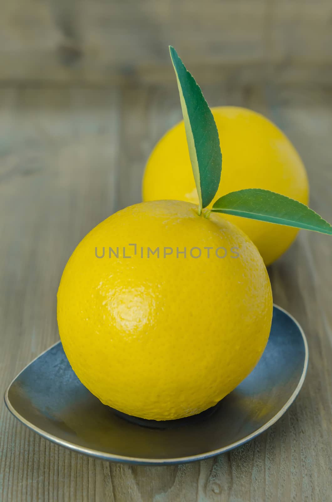 ripe orange with leaves on dish over wooden background