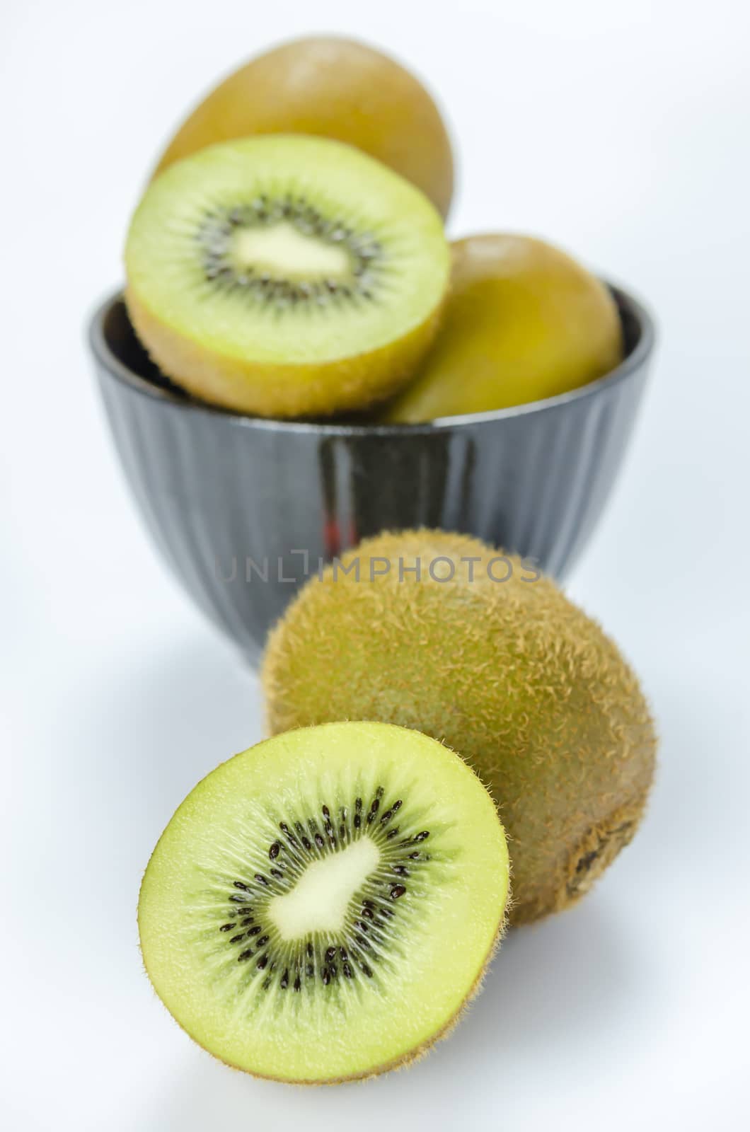 kiwi fruit and half with black bowl on white background