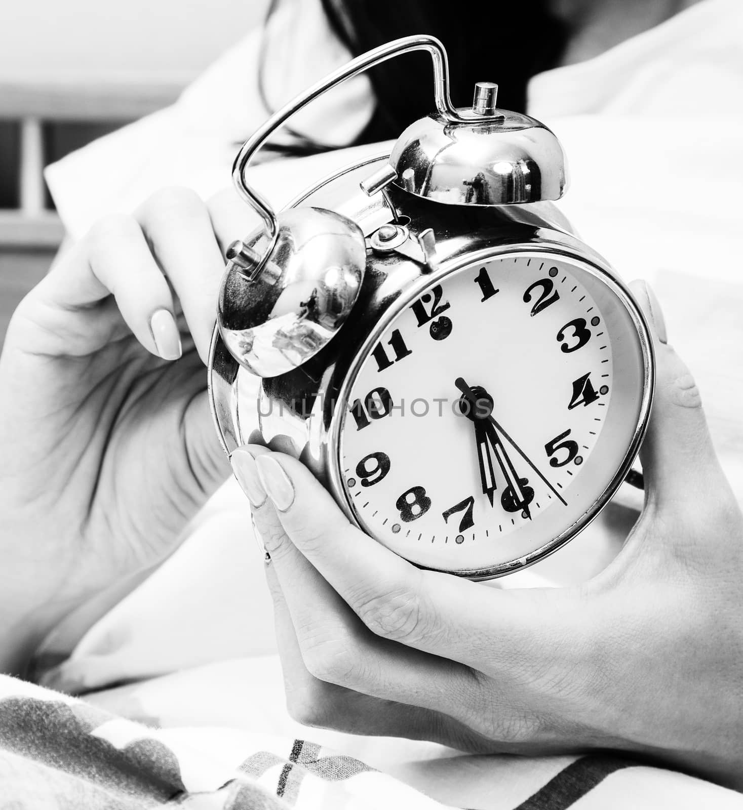 Woman in a bed setting the alarm clock