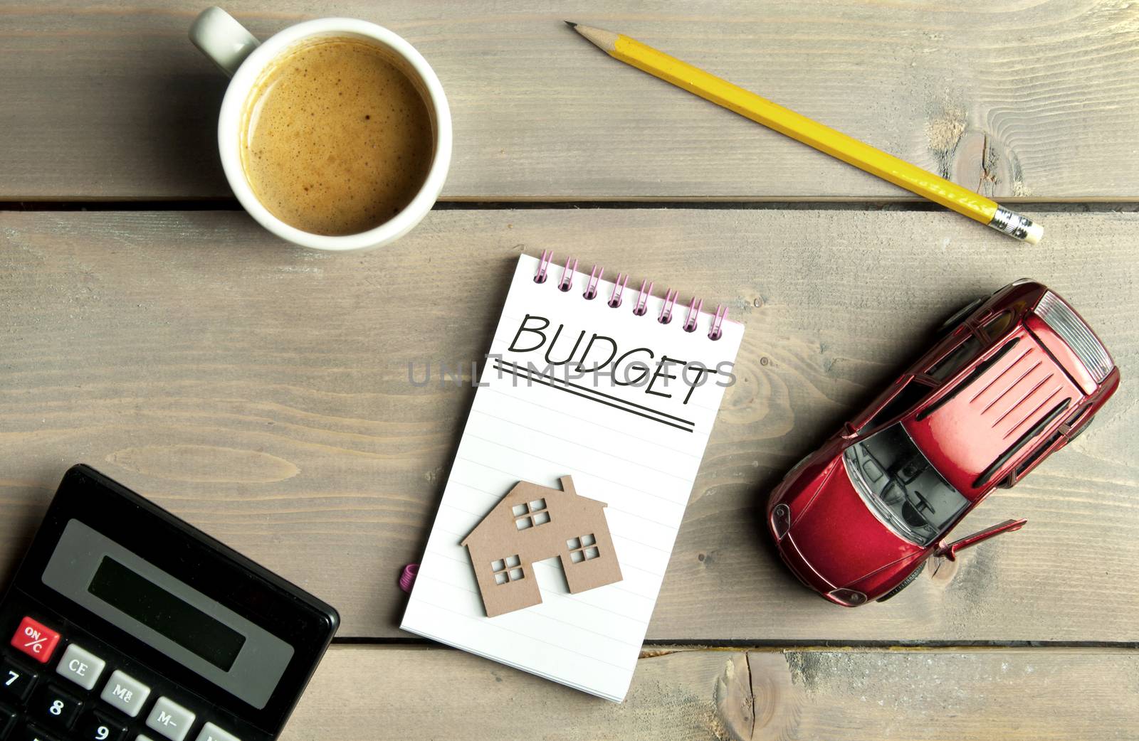 Budget handwritten in a notepad with a miniature car and house