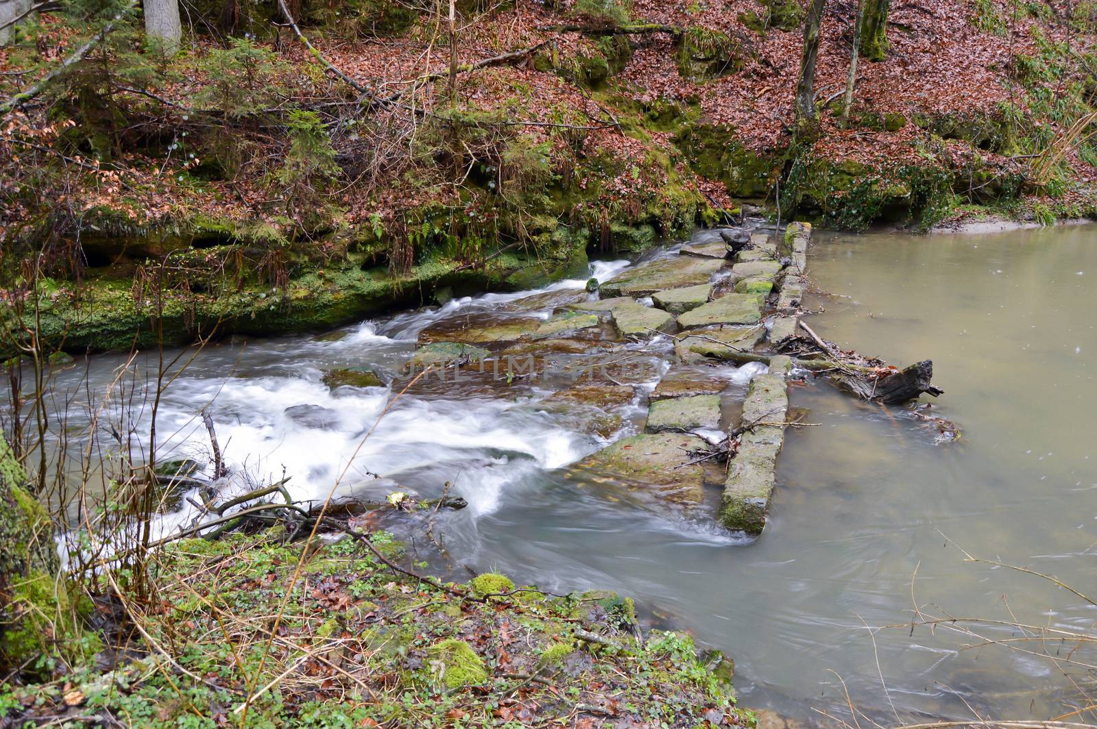 Small waterfall on a stone dam of a small stream in Luxembourg