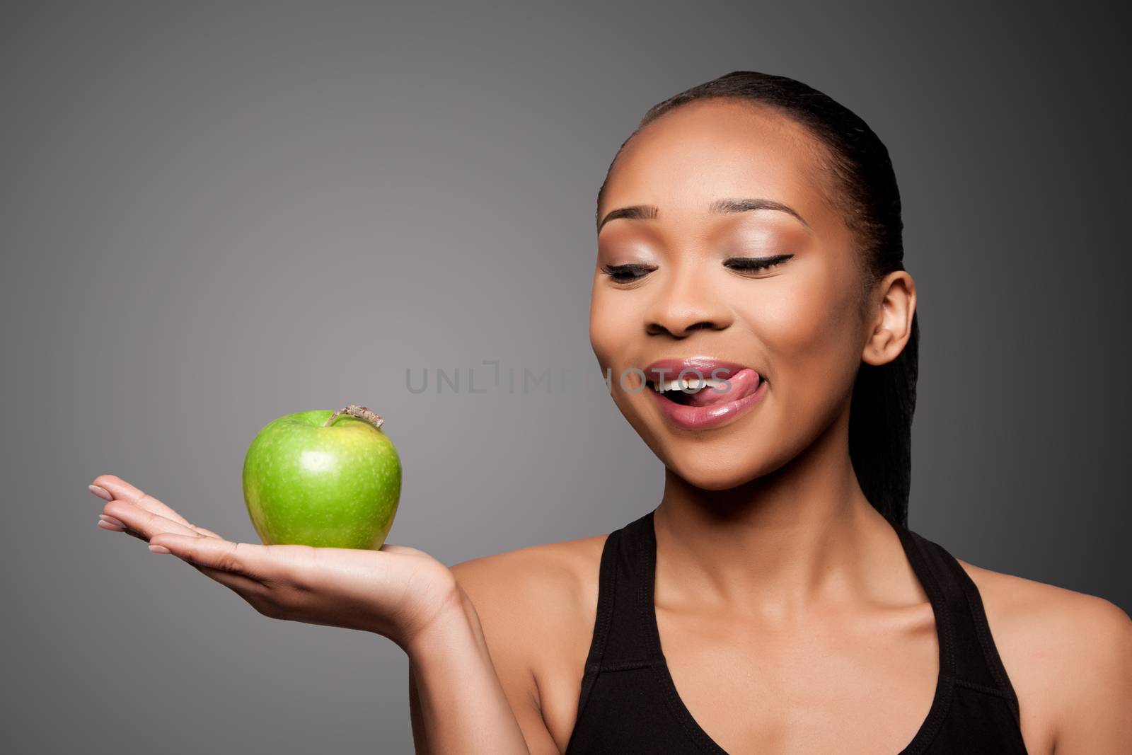 Beautiful healthy happy licking black asian woman with delicious apple in hand.