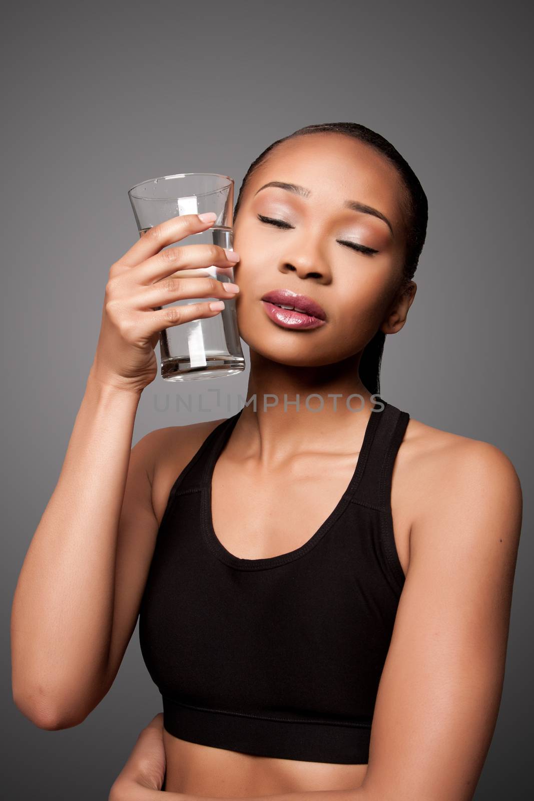 Beautiful healthy black asian woman with glass of water cooling off after workout.