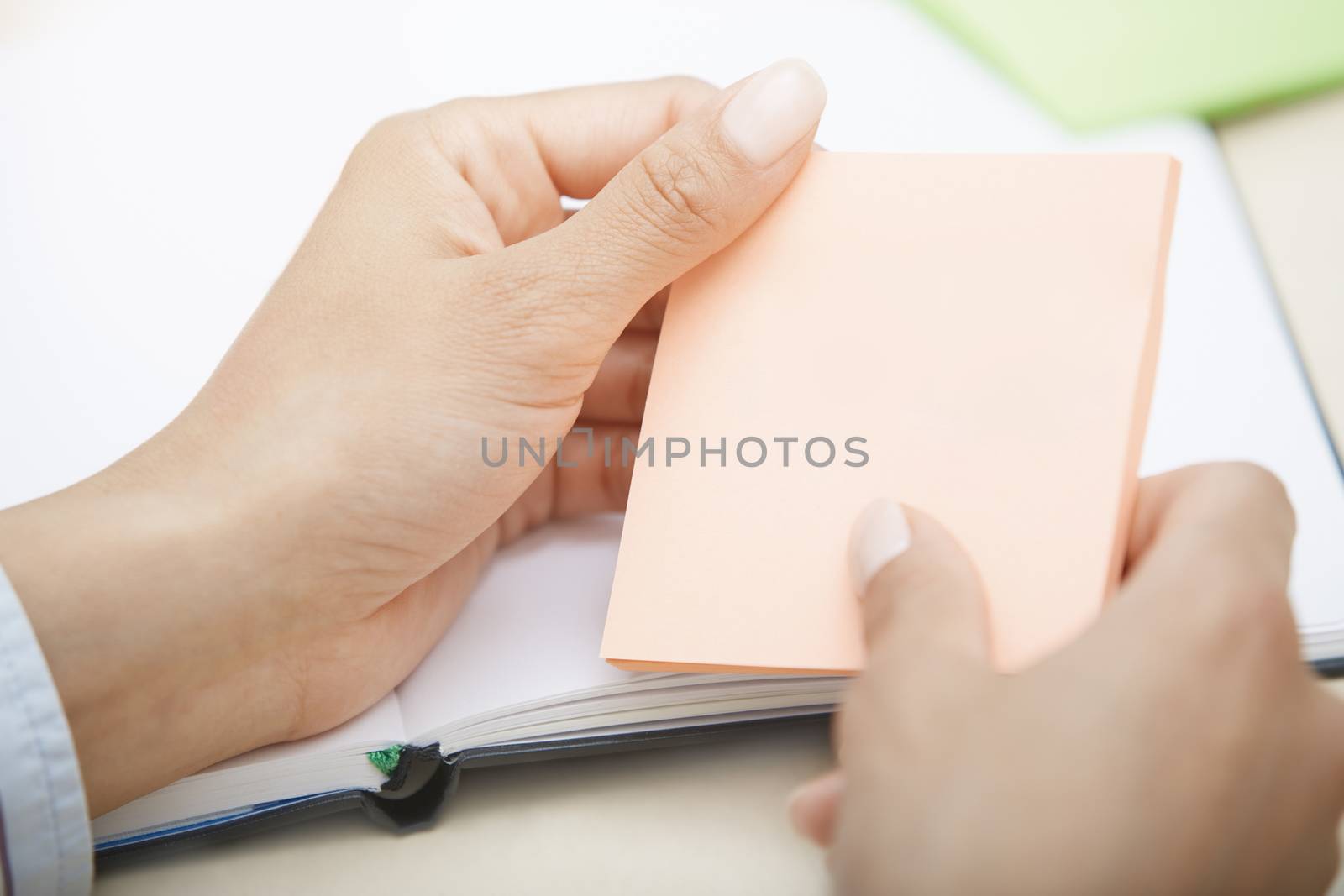 Hands holding pink sticky note with empty space