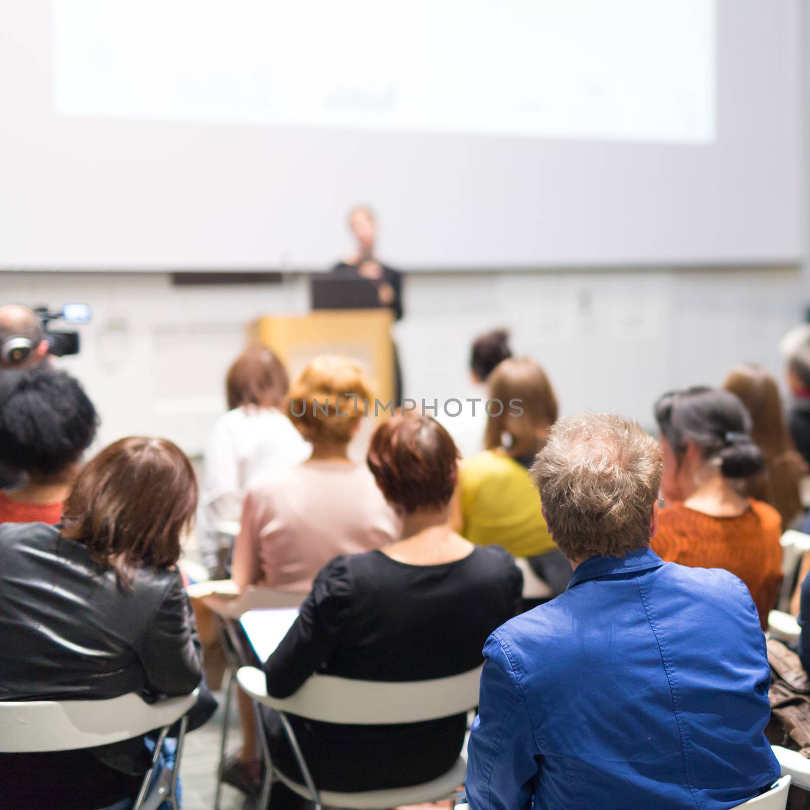 Woman giving presentation in lecture hall at university. by kasto