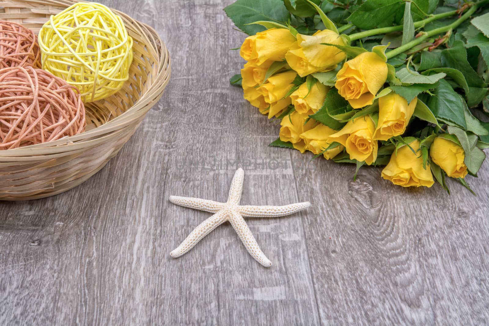 White starfishes and yellow roses on a wooden background
