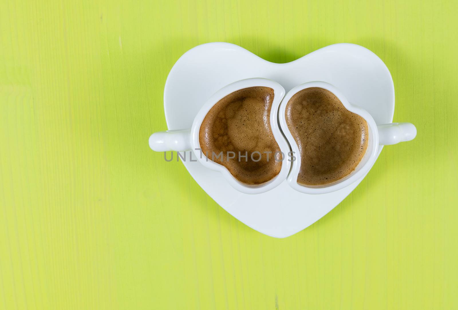 Flat lay with two cups of espresso coffee on a green wooden board. Concept for romance